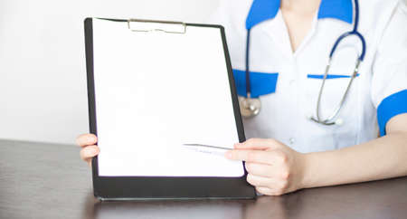 female doctor hand hold silver pen and showing pad. Physical agreement form signature disease prevention ward round reception consent contract sign prescribe remedy healthy lifestyle conceptの写真素材