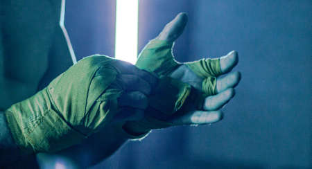 Muscular thai boxing man With yellow Bandages against the dark backgroundの写真素材