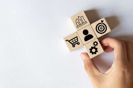 Sale volume increase make business success, Hand holding wood cube with icon goal and shopping cart symbol.の写真素材