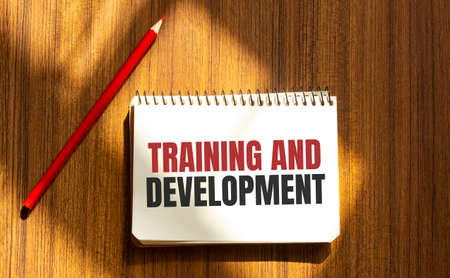 Red pen and notepad with text TRAINING AND DEVELOPMENT in the white backgroundの写真素材