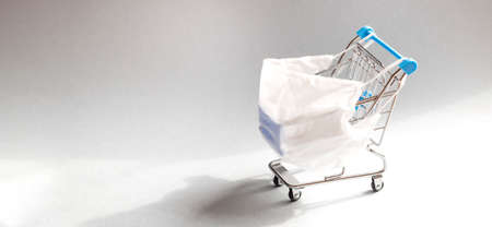 Shopping cart with protective medical mask against coronavirus. Safe and online shopping on...