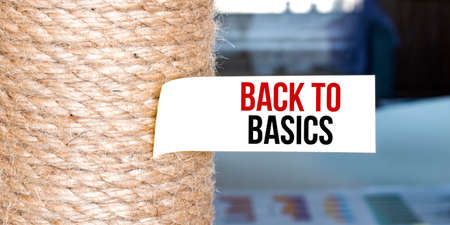 Torn brown paper on white surface with text BACK TO BASICS and answer word.の写真素材