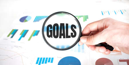 Magnifying glass with words GOALS over wooden background. Business concept.の写真素材