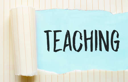 The text TEACHING appearing behind torn white paperの写真素材