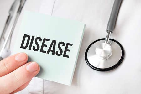 Doctor holding card in hands and pointing the word DISEASEの写真素材