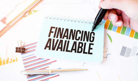 Businessman hand, paper plate, marker, diagram, chart and office tools. Text FINANCING AVAILABLEの写真素材