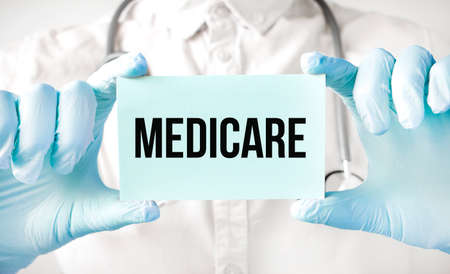 Doctor holding card in hands and pointing the word MEDICAREの写真素材