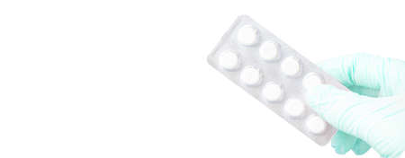 Surgeon's hand in a blue medical glove holds a blister of tablets isolated on a white