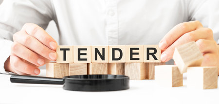 Businessman holding wooden cubes. Businessman watch on the wooden cubes with text TENDER. financial market. financingの写真素材
