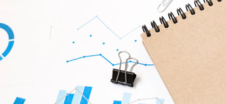 Office desk workplace with pc, paper charts or graph and notebook and pen on wooden table. Top view. release concept.の写真素材