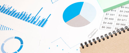 Office desk workplace with pc, paper charts or graph and notebook and pen on wooden table. Top view. release concept.の写真素材