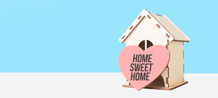 Home sweet home word in wooden heart model and wooden house on blue background.の写真素材