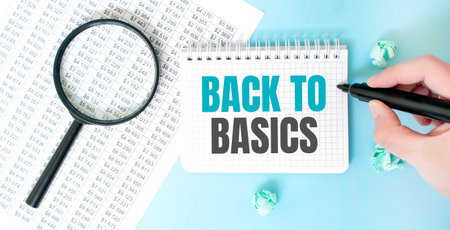 Businesman hand with marker and white noteapad and magnifier on the financial documentation. Text BACK TO BASICS. Business conceptの写真素材