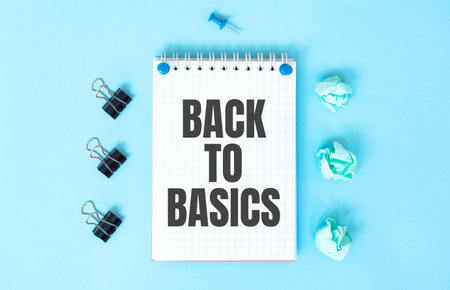 White notepad with text BACK TO BASICS and office tools on the blue backgroundの写真素材