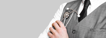 Doctor in suit holding gray stethoscope on gray background