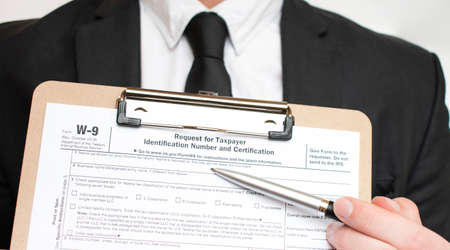 Man holding US tax form W-9. Tax form law document irs business concept