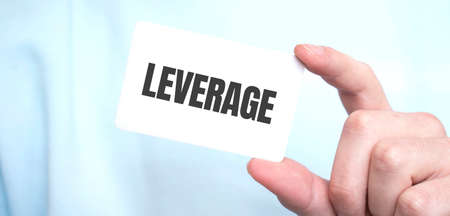 Man in blue sweatshirt holding a card with text LEVERAGE, business concept