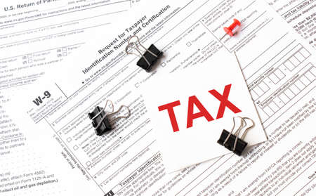 Tax written on white sticker note with paperclip to tax formの写真素材