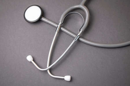 gray stethoscope on dark gray background with cardiogram, health concept