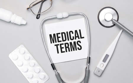 In the notebook is the text MEDICAL TERMS, stethoscope, pills, and glasses.