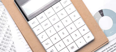 Calculator and an empty Notepad page on the office Desk with financial indicators and charts. Top...