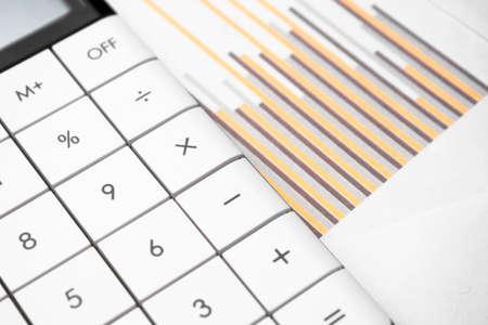 calculator and pen with blue business charts, graphs, information and reports background for...