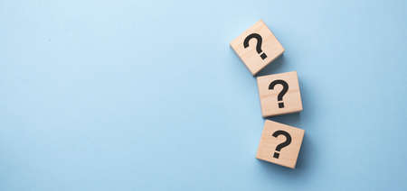 Wooden cube block shape with sign question mark symbol on wood table.