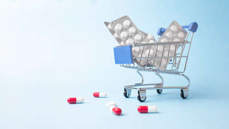 Shopping trolley cart made by pills on light blue background.の写真素材