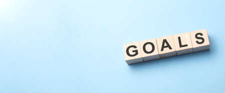 Goals word written on wood block. Goals word is made of wooden building blocks lying on the blue table. Business concept, yellow backgroundの写真素材