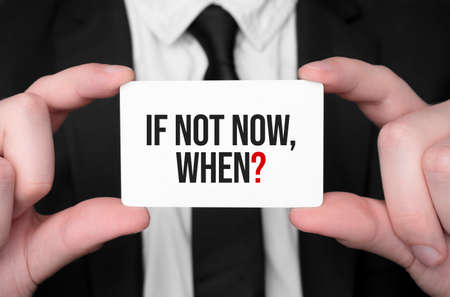Businessman holding a card with text if not now, whenの写真素材