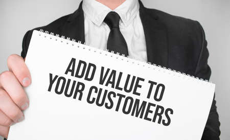 Businessman holding a card with text ADD VALUE TO YOUR CUSTOMERSの写真素材