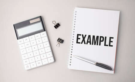The word EXAMPLE is written on a white background next to a pen, calculator and reports. Business conceptの写真素材