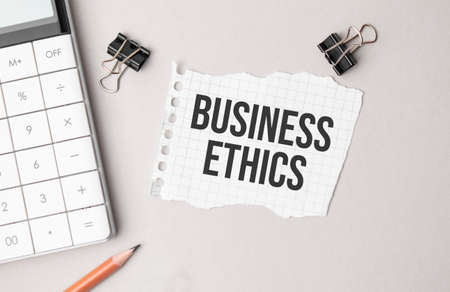 Business concept. Notebook with text BUSINESS ETHICS sheet of white paper for notes, calculator, glasses, pencil, pen, in the white backgroundの写真素材