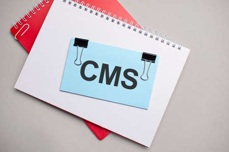 Blue colored stick with text CMS on the white and red notepadの写真素材