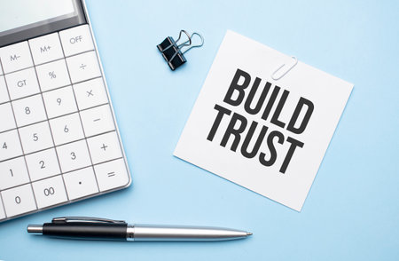 On a blue background, glasses, calculator, coffee, magnifier, pen and notebook with the text BUILD TRUSTの写真素材