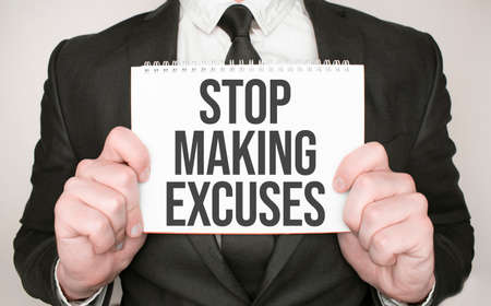 Businessman holding a notepad with text STOP MAKING EXCUSESの写真素材