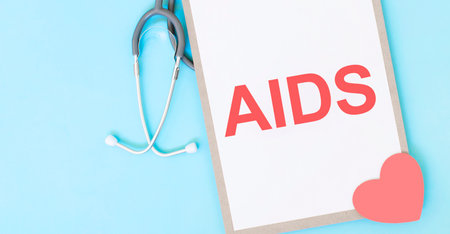 Gray stethoscope and paper plate with a sheet of white paper with text aids light blue backround. Medical concept.の写真素材