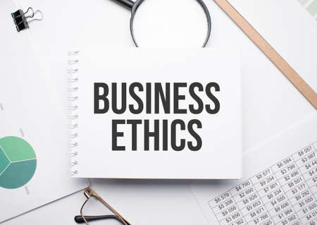 On the notepad for writing the text BUSINESS ETHICS, magnifier, charts and glasses.