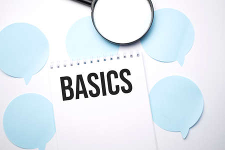 White noteapad and magnifier on blue speech bubles. Text BASICS. Business concept