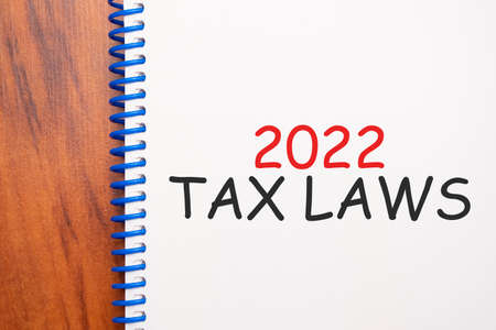 Text 2022 Tax Laws written in notepad, Office wood table from above, concept image for blog title or header image. Aged vintage color look.の写真素材