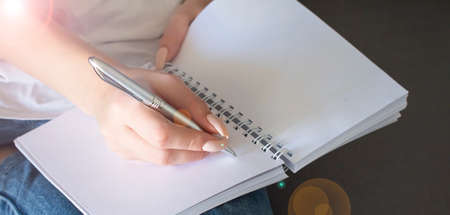 Woman's hand using a pencil noting on notepad