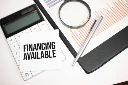 Business accessories, calculator, reports and magnifier glass with text financing availableの写真素材