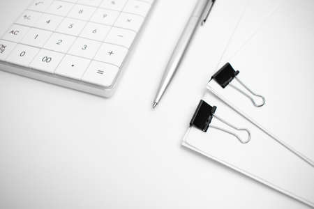 Calculator, pen, white paper for notes lie on the surface of a wooden table