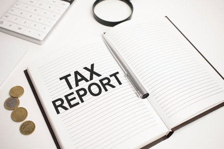 Business accessories, calculator, coins, reports and magnifier glass with text tax reportの写真素材