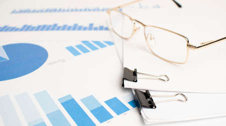 On documents with colored columns of numbers is a pen glasses and Notepad. Business concept