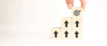 Achievement business target concept, businessman holding and stacking wooden cubes block which print screen target, mechanical gear, light bulb.の写真素材