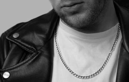 man in leather jacket looks to side while sitting on a stool in studioの写真素材