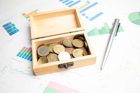 top view of business chart on white wooden table with coins, wood box and penの写真素材
