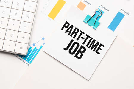 Part-time job text concept. Office workplace table with calculator, graphs, reports and the text Budget 2021 on a small piece of paper on multicolored background.の写真素材