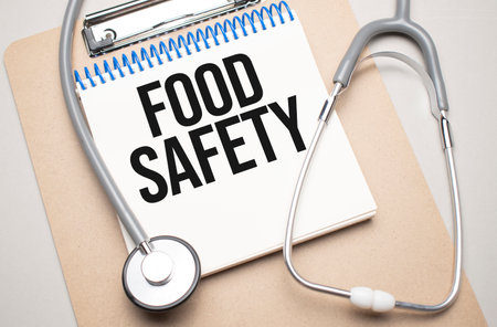 White notepad with the words food safety and a stethoscope on a blue background. Medical conceptの写真素材